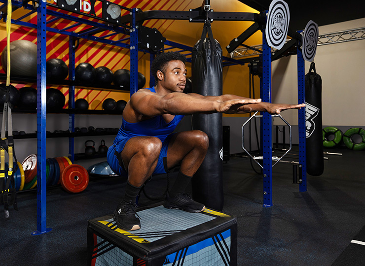gym goer squating on box jump