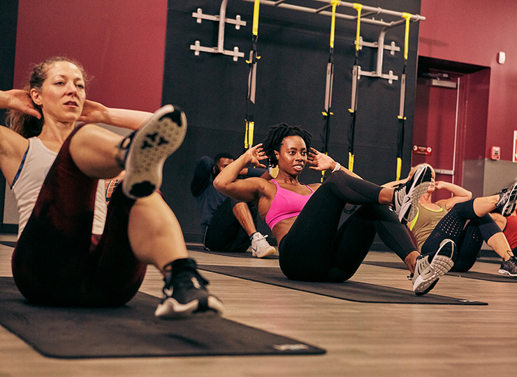 Group fitness class doing bicycle crunches on mats.
