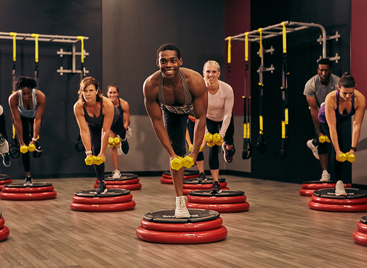 Group fitness class balancing on step platforms with dumbbells.