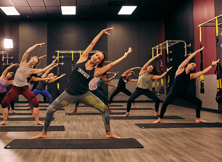 : Group fitness class doing side bends in a studio.