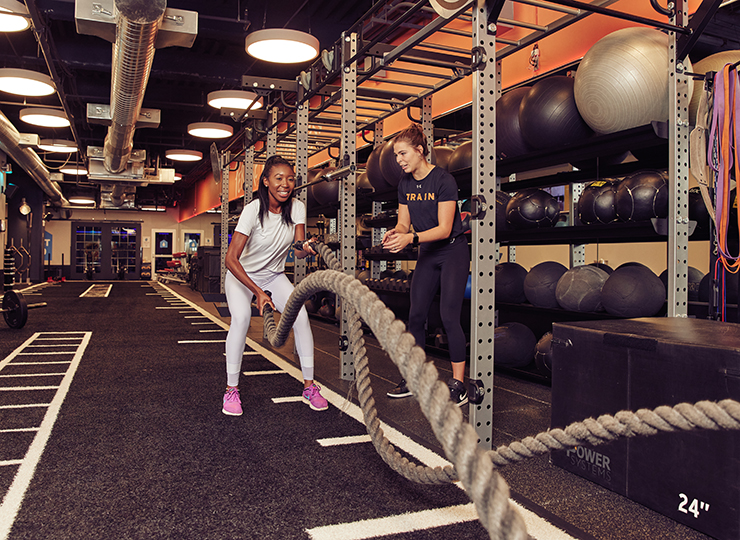 A trainer helping a woman in the HIIT Zone