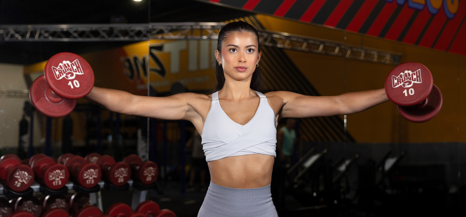 Woman doing dumbbell lateral raises in the gym.