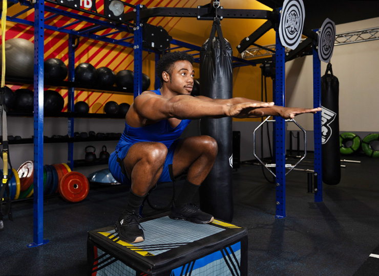 Man doing a squat on a platform in the gym.