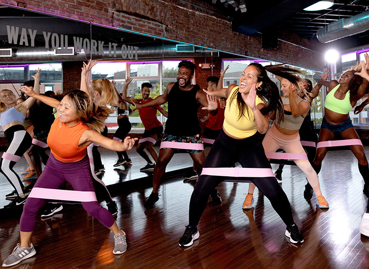 gym-goer participating in group fitness dance/cardio class with resistance bands